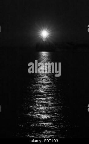 Newhaven Leuchtturm auf Juli Nacht, mit Reflexionen auf dem Wasser. Schwarz und Weiß. Stockfoto