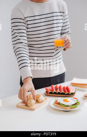 Ein Mann essen Frühstück und lesen Buch zu Hause am Morgen. Stockfoto