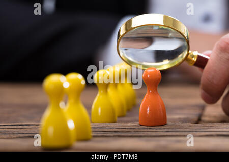 Der Unternehmer Hand mit Lupe über orange Bauer auf hölzernen Schreibtisch Stockfoto