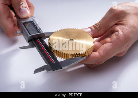 Einer Person die Hand des Messgetriebe Größe mit digitalen elektronischen Messschieber auf weißem Hintergrund Stockfoto