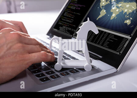 Nahaufnahme der Hand der Hacker Hacking globales Netzwerk mit Trojan Horse Symbol auf Laptop Stockfoto