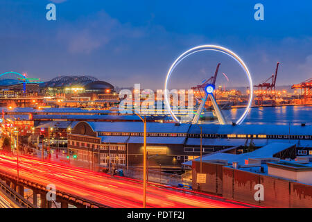 Seattle, WA - Februar 27, 2017: Seattle Waterfront bei Sonnenuntergang mit großen Rad und Verkehr trail leuchtet Stockfoto