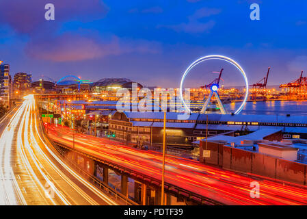 Seattle, WA - Februar 27, 2017: Seattle Waterfront bei Sonnenuntergang mit großen Rad und Verkehr trail leuchtet Stockfoto