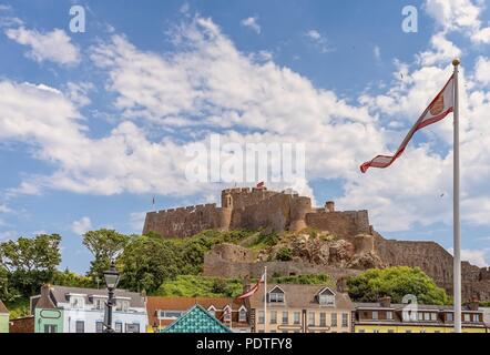 Gorey (Mont Orgueil) Schloss in Jersey. Gebäude sind unten und eine Flagge in den Vordergrund gelegen. Stockfoto