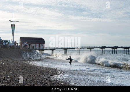 Surfer, die sich aus dem Meer in Saltburn-by-the-Sea, North Yorkshire, England. Die Leute zu beobachten die Wellen vom Meer an der Wand. Stockfoto