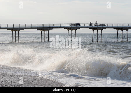 Lebhafte Brandung am Strand von Saltburn-by-the-Sea, North Yorkshire, England. Der Pier im Hintergrund. Stockfoto