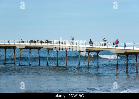 Die Menschen genießen einen entlang der alten Pier spazieren an Saltburn-by-the-Sea an der Küste von North Yorkshire, England. Einen schönen Frühlingsabend. Stockfoto