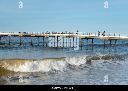 Die Menschen genießen einen entlang der alten Pier spazieren an Saltburn-by-the-Sea an der Küste von North Yorkshire, England. Einen schönen Frühlingsabend. Stockfoto