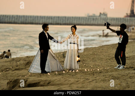 Hochzeit am Strand, Sonnenuntergang, Kamera, Haltung, Hände halten Paar Stockfoto