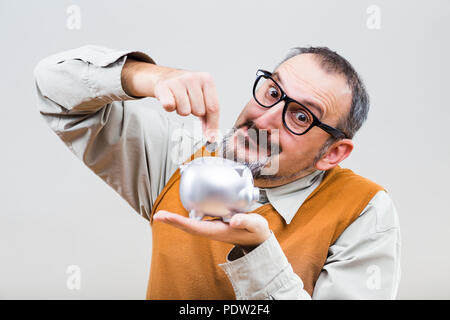 Nerdy Mann ist die Münze in Sparschwein. Stockfoto