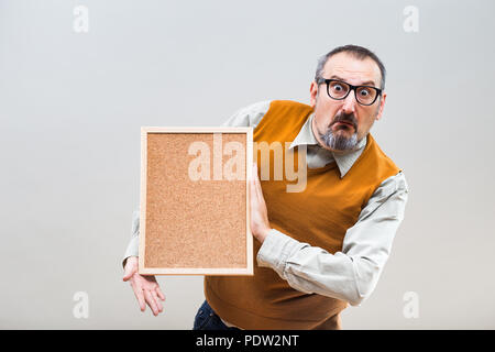 Nerdy Geschäftsmann ist wegen etwas, während Sie leere Cork board verwirrt. Stockfoto