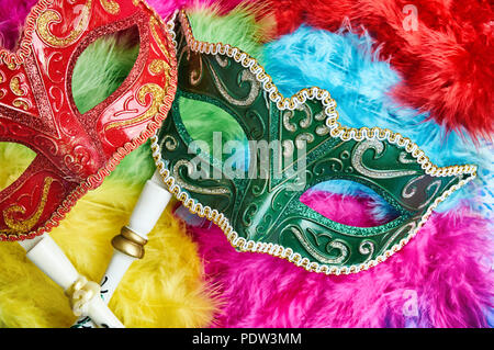- Schließen Sie die roten und grünen Karneval Maskerade, Venezianische Maske (Oper Maske) mit weißem Holz Griff auf die bunten weichen, flauschigen federn in Gelb, Rosa Stockfoto