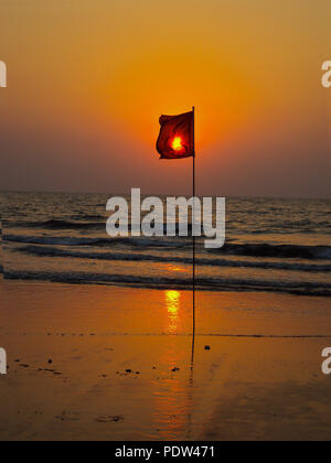 Eine rote Flagge vor die untergehende Sonne über dem Indischen Ozean Stockfoto