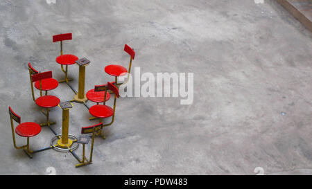 Leer gebrochen Park roten Stühlen auf einem Betonboden Stockfoto