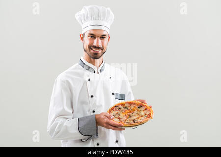 Koch Holding Pizza auf grauem Hintergrund. Stockfoto
