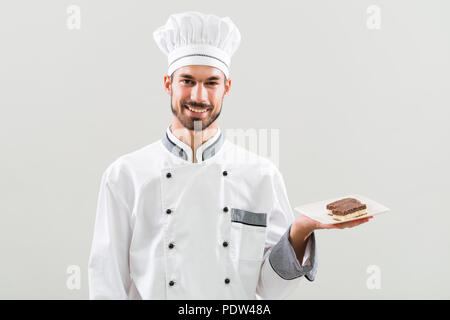 Konditor zeigt Scheiben von Kuchen auf grauem Hintergrund. Stockfoto