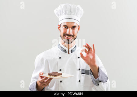 Konditor zeigt Scheiben von Kuchen auf und zeigt ok Zeichen grauen Hintergrund. Stockfoto