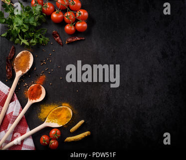 Verschiedene Gewürze auf rustikalen schwarzer Hintergrund mit Copyspace. Stockfoto