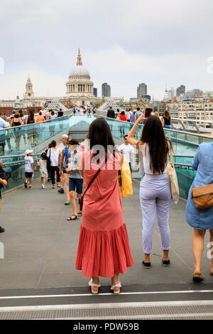 Weibliche Touristen stop Fotografien auf der Londoner Millennium Bridge in Richtung St Pauls Kathedrale suchen. London, England Stockfoto