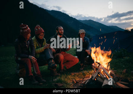 Freunde singen und spielen Gitarre am Lagerfeuer Stockfoto
