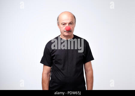 Älterer Mann im schwarzen T-Shirt stand mit roter Clown Nase in Depressionen. Er ist Leiden allein zu sein. Stockfoto