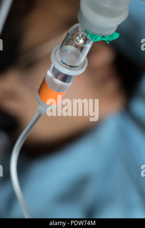 Close up Kochsalzlösung Tropfen mit einem Patienten liegen auf einem Bett im Hintergrund. Stockfoto