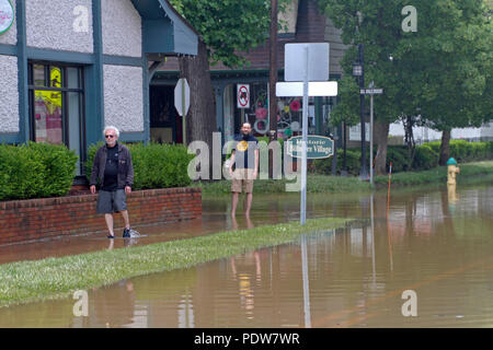 BILTMORE Village, South Carolina, USA - 30. MAI 2018: Zwei Männer Knöchel tief Furt durch Hochwasser, dass der Bürgersteig und Straße im Biltmore Villa umfasst Stockfoto