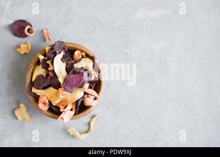 Verschiedenen pflanzlichen Chips auf grauem Hintergrund, kopieren. Verschiedene getrocknete rote Beete, Karotten, Kürbis Gemüse Chips - gesunden veganen Snack. Stockfoto