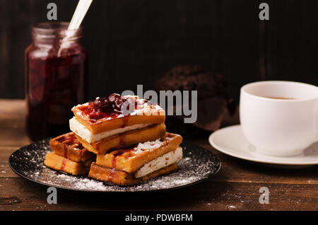 Wiener Waffel in Kirsche Sirup auf einem dunklen Hintergrund mit Tasse Tee Stockfoto