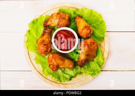 Gebratene Flügel mit Ketchup auf einem hölzernen backround Nahaufnahme Stockfoto