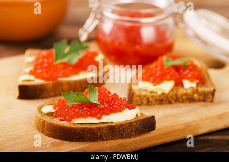 Roter Lachskaviar im Sandwich und Glas auf einem Holztisch Stockfoto