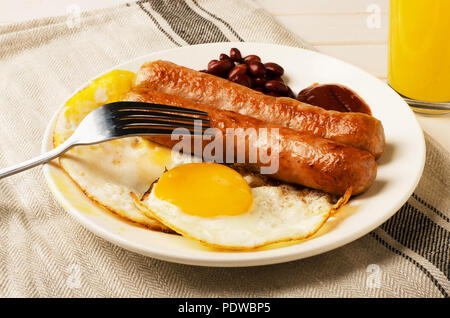 Frühstück gebratene Eier und Würstchen mit Orangensaft Stockfoto