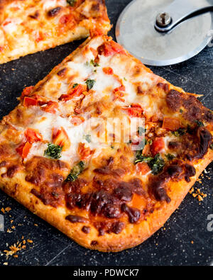 Quadratische Scheiben köstliche italienische Pizza Margarita an Bord mit Schneidevorrichtung Stockfoto