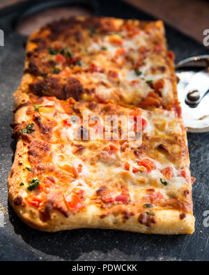 Quadratische Scheiben köstliche italienische Pizza Margarita an Bord mit Schneidevorrichtung Stockfoto