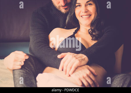 Paare, die in Liebe zu Hause legte sich auf das Bett lächeln und schauen sich gegenseitig mit Zärtlichkeit. Kaukasier, Innen- Aktivität. Sie schwanger für neue Familie und Stockfoto