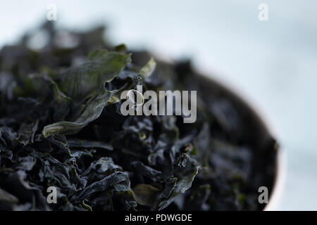 Nahaufnahme von einem Stapel der getrockneten Blätter von Wakame, einem Asiatischen essbare Algen in der traditionellen Suppen wie die Miso Suppe verwendet werden, auf einem weißen Keramik Schüssel Stockfoto