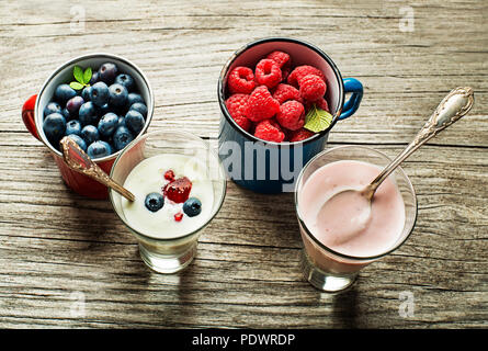 Schale mit frischem gemischte Beeren und Joghurt mit frischen Blaubeeren, Himbeeren, serviert auf einem Holztisch Stockfoto