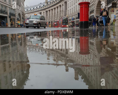 Regents Street. London. UK 10 Aug 2018 - eine Reflexion von schwarzen Londoner Taxis und einen Briefkasten in einer großen Pfütze von Regenwasser in der Regent Street nach einem schweren Regenfällen in Central London. Kredit Roamwithrakhee/Alamy leben Nachrichten Stockfoto