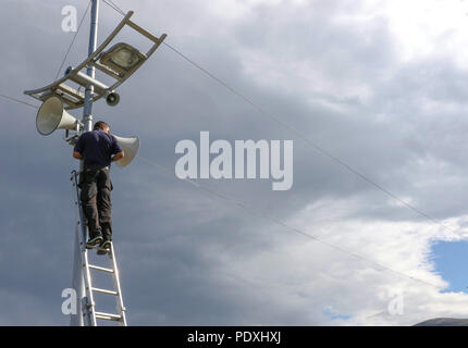 Newcastle, County Down, Nordirland. 10. August 2018. UK Wetter - eine Verbesserung der Bild über County Down am Nachmittag mit schweren Duschen mit sonnigen Abschnitten. Morgen (Samstag) sieht die jährliche Festival der Newcastle Flug Platz an der Küstenstadt. Ein Techniker auf einer Leiter arbeiten an der Lautsprecheranlage. Copyright David Hunter/Alamy Leben Nachrichten. Stockfoto