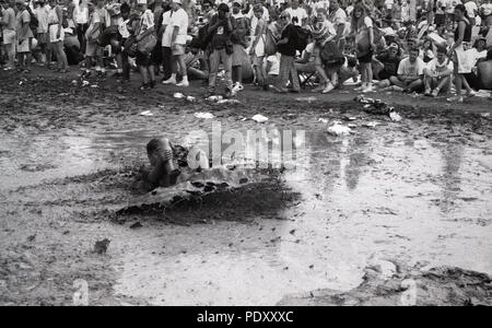 Jungen Erwachsenen Mannes Gleiten im Schlamm beim Woodstock Festival, Kingston, New York, USA, 13. Juli 1994 Stockfoto