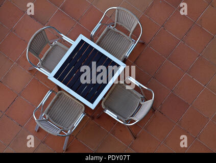 Vier Stühle aus Rattan um einen Tisch auf braunen Fliesen Pflaster Stockfoto