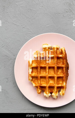 Traditionelle belgische Waffel auf rosa Platte über konkrete Oberfläche, Ansicht von oben. Nahaufnahme. Stockfoto