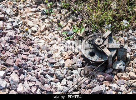 Alte Riemenscheibe aus Stahl mit dem metall draht auf dem steinernen Boden für die Ampel Pol in der Nähe des Bahnhof, Thailand. Stockfoto