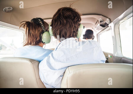 Junge touristische Paar, eine kleine Fläche. Das Tragen von Headsets und Miteinander zärtlich während des Fluges. Stockfoto