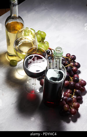 Weißwein und Rotwein in ein Glas mit Herbst Trauben, weißen Stein Hintergrund Stockfoto