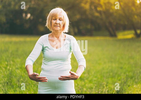 Ältere Frau genießt Übung Tai Chi in der Natur. Bild ist absichtlich abgeschwächt. Stockfoto