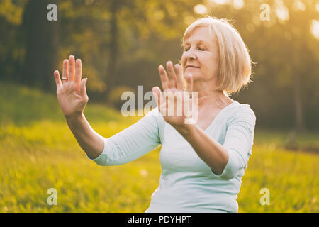 Ältere Frau genießt Übung Tai Chi in der Natur. Bild ist absichtlich abgeschwächt. Stockfoto
