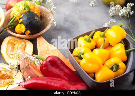 Paprika gelb und rot, Kartoffeln und Kürbis auf grauem Hintergrund. Die Ernte ist herbstlich. Freier Platz für Text, Rahmen. Ansicht von oben. Stockfoto
