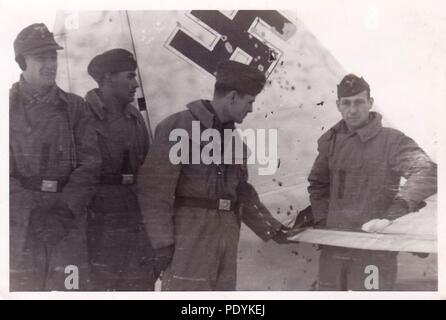 Bild aus dem Fotoalbum von Feldwebel Willi Hoffmann von 5. Staffel, Kampfgeschwader 30: Willi Erkens und seine Mannschaft aus der 5./KG 30 posieren vor ihrem Winter getarnte Junkers Ju 88 Bomber, nach einem Treffer von Flak auf der rechten Stabilisator im Winter 1941/42. Von links nach rechts: Unteroffizier Otto Bienmüller (Radio Operator), Gefreiter Willi Hoffmann (Air Gunner), Feldwebel Willi Erkens (Pilot) und Feldwebel Richard Müller (Beobachter -, die in der Bohrung durch eine Shell). Die gesamte Besatzung konnte von einer Mission im Mittelmeer am 23. Januar 1943 zurückzukehren. Stockfoto