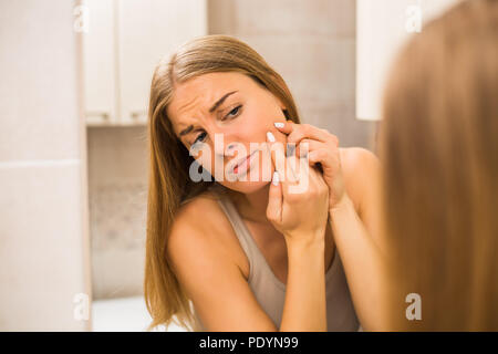 Junge Frau quetschen Pickel im Bad. Stockfoto